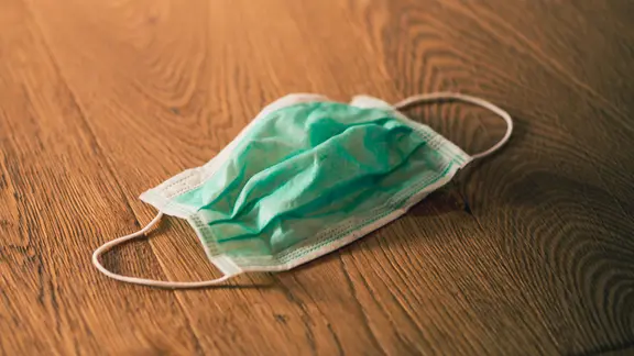 Eine Maske liegt auf einem Holzuntergrund.