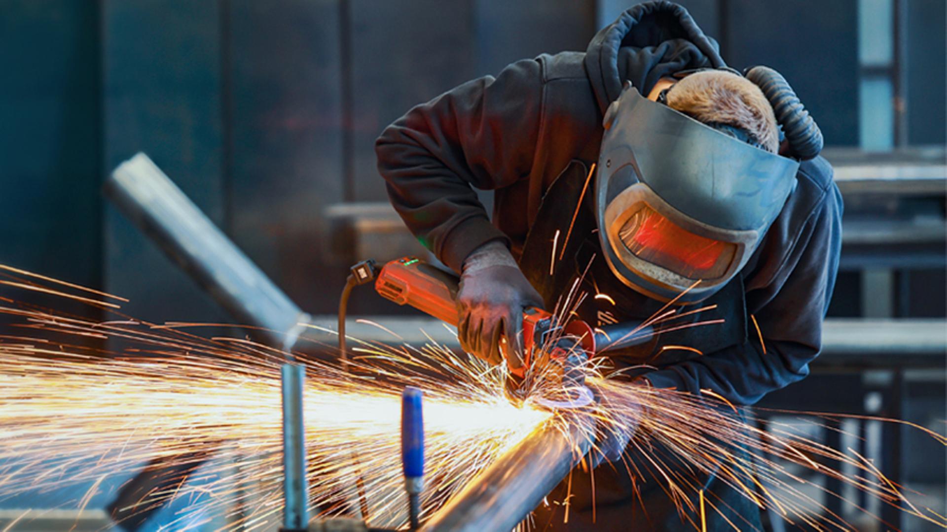 Ein Industriearbeiter flext mit einem Winkelschleifer ein Stahlrohr. (Themenbild) | picture alliance, Rupert Oberhäuser