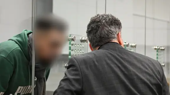 Der Angeklagte (l), mutmaßliches Mitglied der Hisbollah, steht im Oberlandesgericht hinter einer Glaswand.