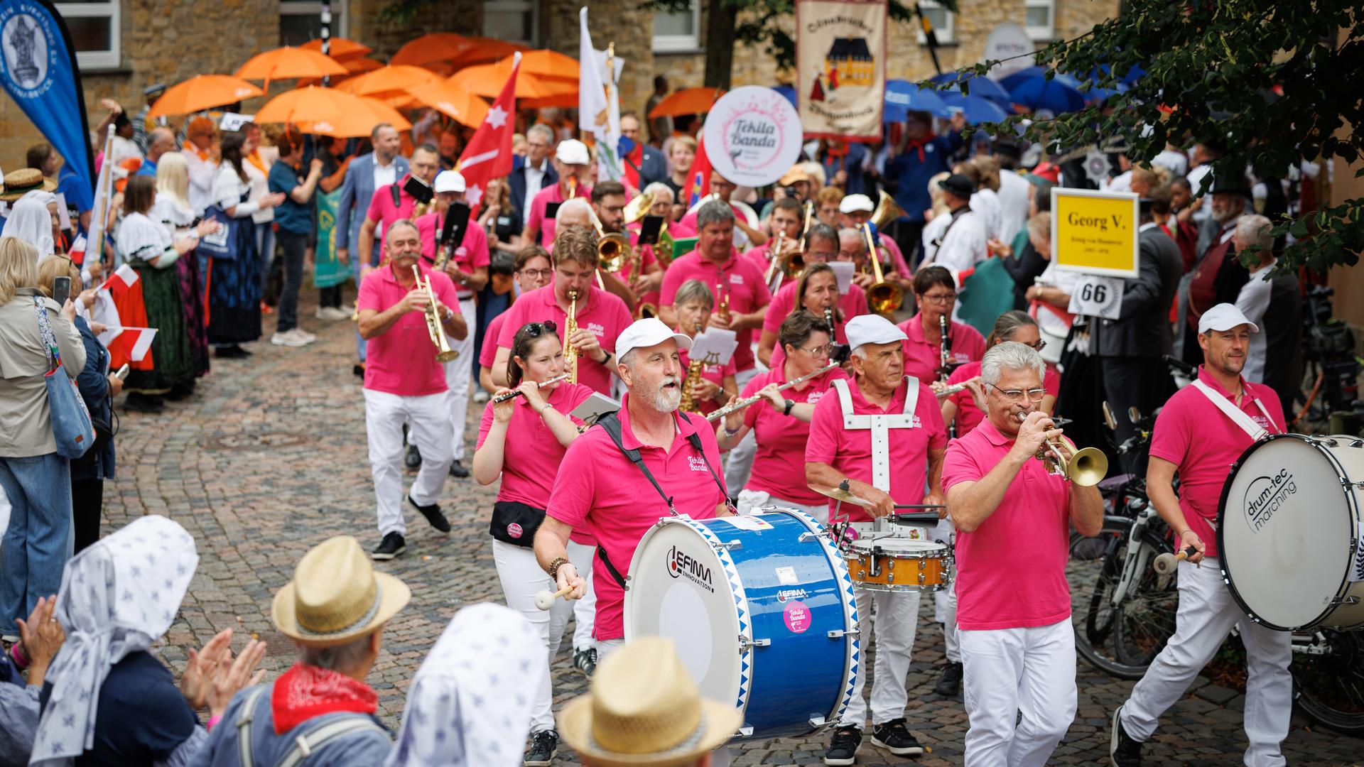 Eine Blaskapelle mit lila T-Shirts läuft durch eine Osnabrücker Straße. | picture alliance/dpa | Friso Gentsch