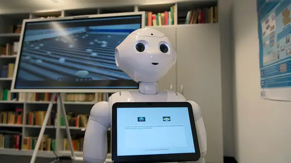 Roboter Pepper vor Bücherwand.