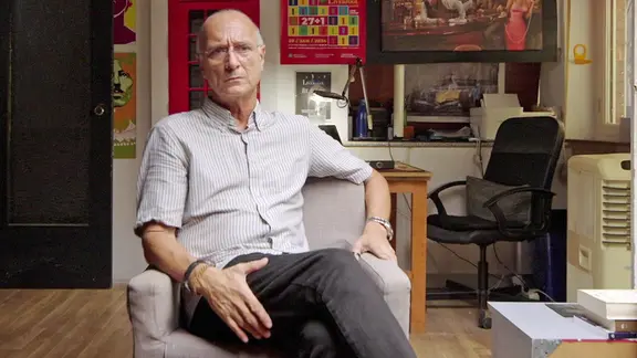 Carlos Leiva ist sich keiner Schuld bewusst, das kleine Mädchen Ruby nach Deutschland gebracht zu haben. | NDR Leihmutterschaftsagent Carlos Leiva sitzt während eines Interviews auf einem Stuhl.