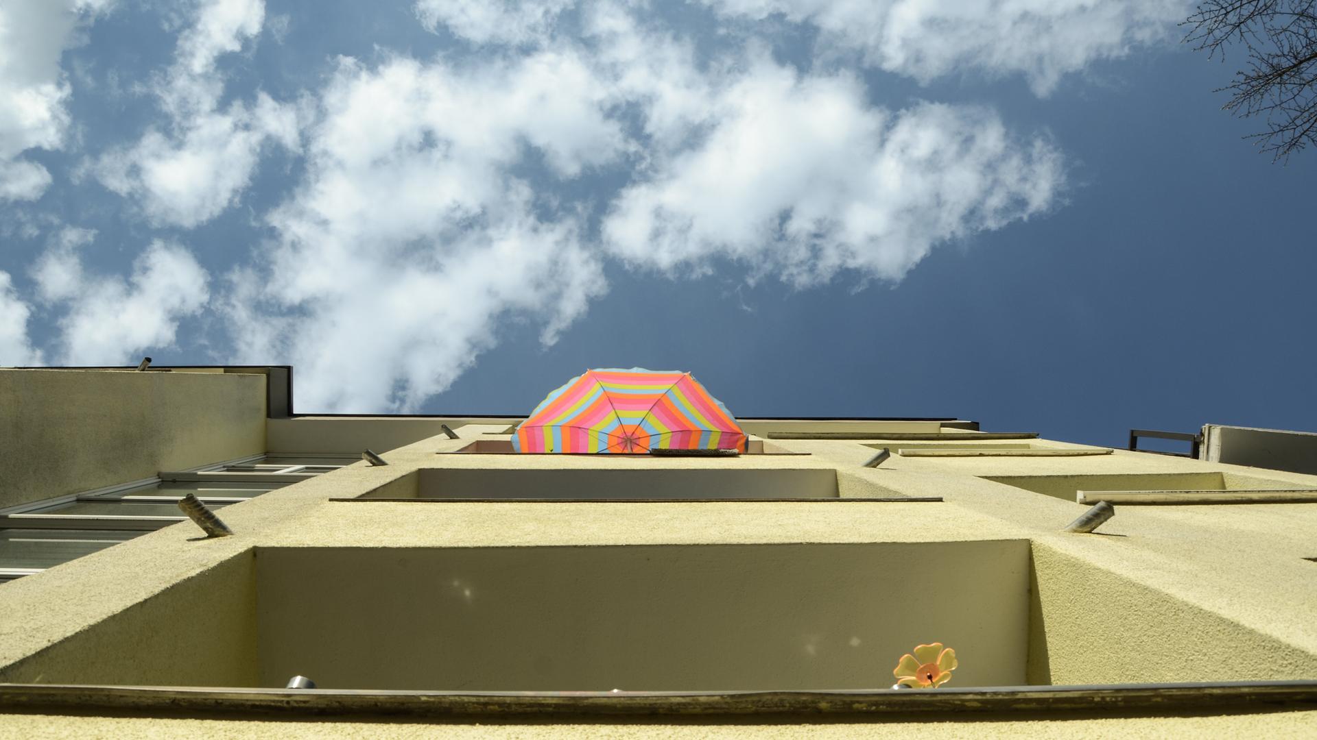 Blick nach oben auf die Balkone eines Mehrfamilienhauses mit Sonnenschirm und blauem Himmel. | picture alliance / DWerner/Shotshop | DWerner