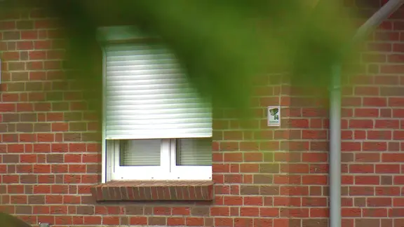 Beamte der Spurensicherung stehen im Emder Stadtteil Larrelt vor einem Einfamilienhaus.