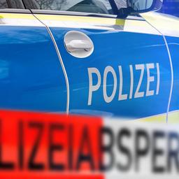 Ein Absperrband der Polizei vor einem Einsatzfahrzeug.