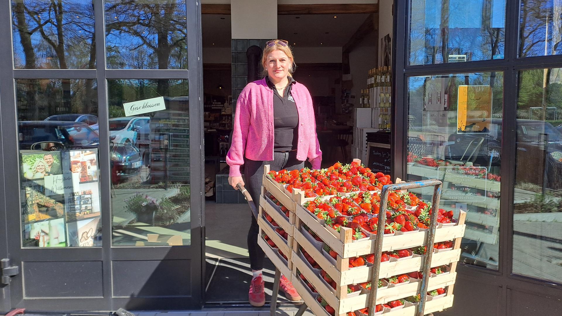 Karina Kock fährt eine Schubkarre mit zwei Kisten voll Erdbeeren in den Hofladen | Lena Bathge