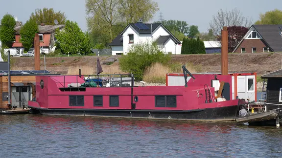Das rosafarbene Hausboot, in dem eine 58-jährige Frau tot aufgefunden wurde, liegt an einem Steg im Holzhafen im Hamburger Stadtteil Moorfleet. | picture-alliance/dpa, Marcus Brandt Das rosafarbene Hausboot, in dem eine 58-jährige Frau tot aufgefunden wurde, liegt an einem Steg im Holzhafen im Hamburger Stadtteil Moorfleet.