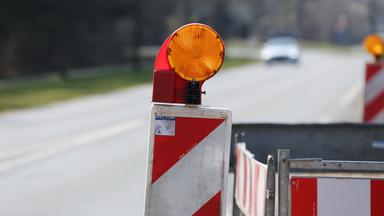 Baustellenbaken und Absperrzaun stehen am Straßenrand.