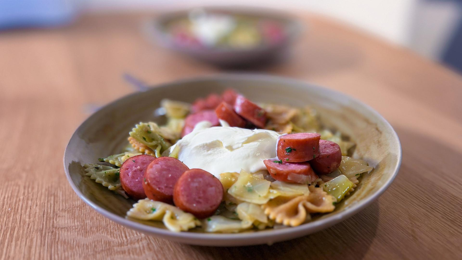 Krautfleckerl mit Farfalle, Kochwurst und Crème fraîche auf einem rustikalen Teller angerichtet | NDR