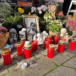 Auf einer Straße stehen Trauerkerzen, Blumen, ein Engel und ein Bild.