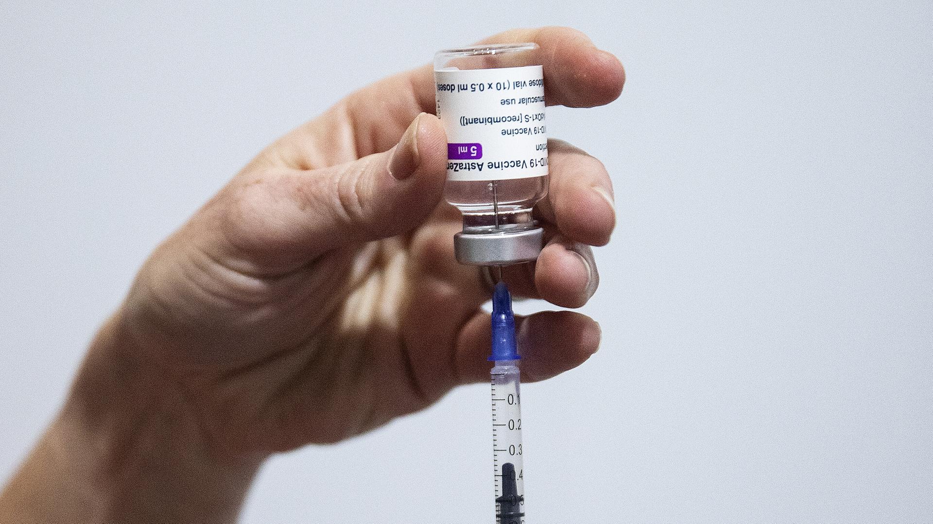 Zwei Hände ziehen mit einer Spritze Impfstoff aus einer Ampulle. | picture alliance / empics | Brian Lawless