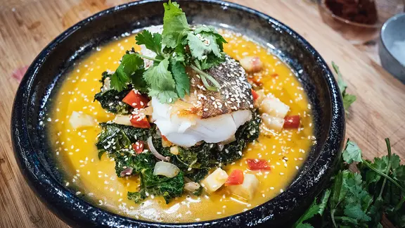 Grünkohl-Curry mit gebratenem Kabeljaufilet auf einem dunklen Teller | NDR, Tarik Rose Grünkohl-Curry mit gebratenem Kabeljaufilet auf einem dunklen Teller