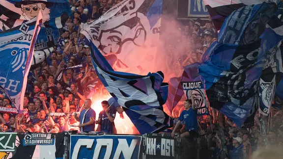 HSV-Fans schwenken Fahnen und brenen Pyro-Technik ab.