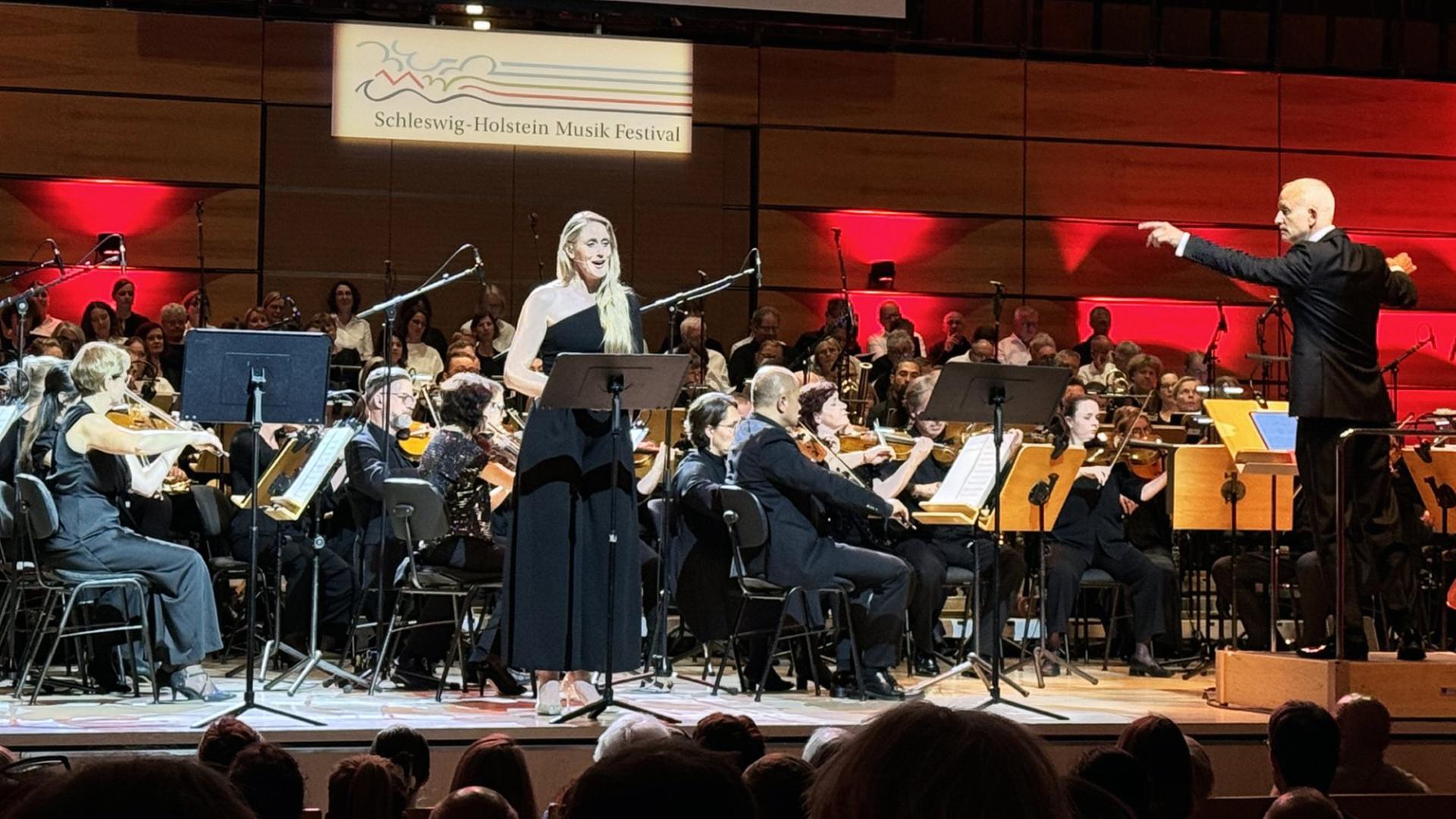 Sängerin Melanie Gebhard, Dirigent Nicolas Fink und The Danish Philharmonic spielen auf einer Bühne.  | NDR, Foto: Inessa Baur