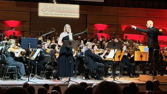 Sängerin Melanie Gebhard, Dirigent Nicolas Fink und The Danish Philharmonic spielen auf einer Bühne. 