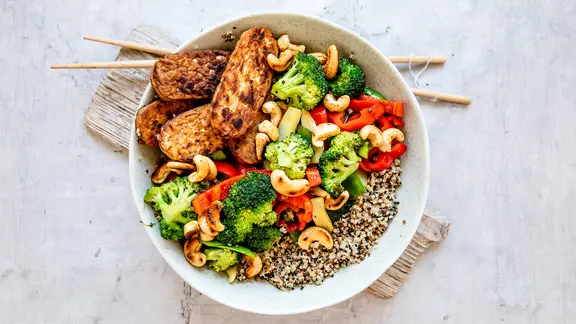 Eine Wok-Pfanne mit Gemüse, gebratenem Tempeh und Quinoa.