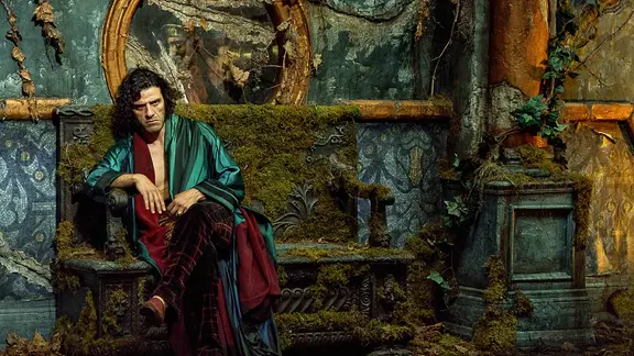 Oscar Isaac sitzt als Victor Frankenstein grimmig auf einer moosbewachsenen Bank (Szenenbild)