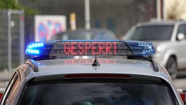Auf einem Polizeifahrzeug steht "Gesperrt".