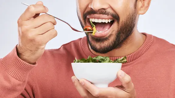 Ein Mann isst Salat.