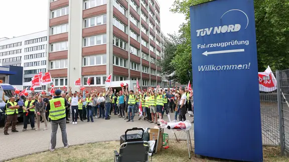 Streikende stehen bei einem Warnstreik bei der TÜV