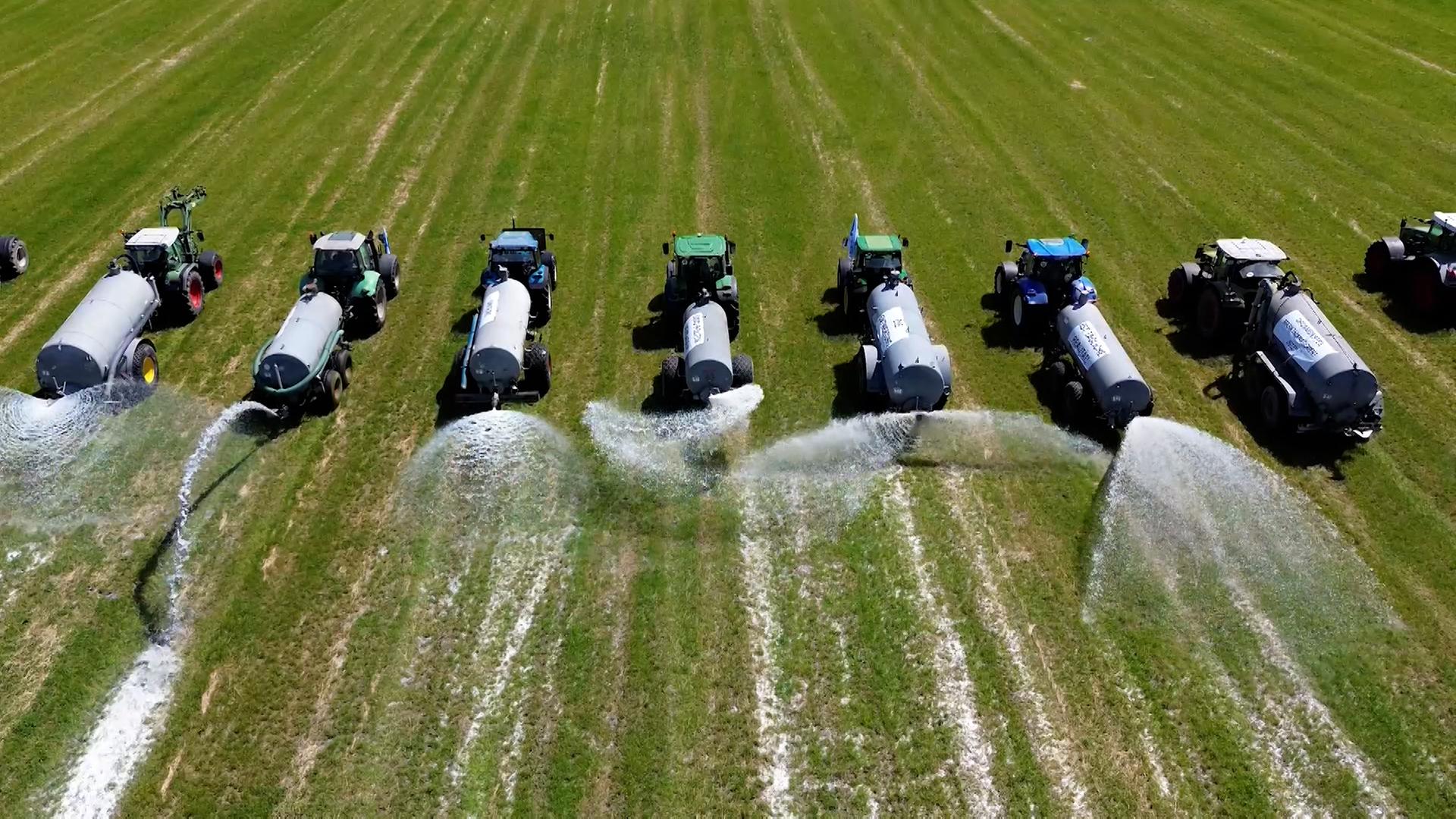 Bauern versprühen bei einer Protestaktion Milch auf einem Feld. | NonstopNews