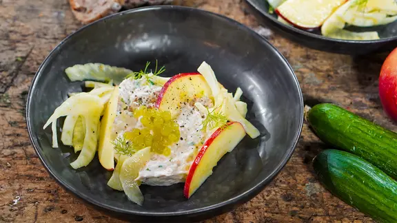 Räucherfisch-Tatar mit Apfel-Fenchelsalat und Gurkenkaviar auf einem Teller serviert