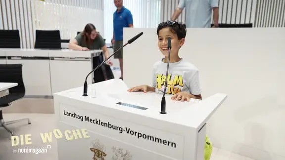 Ein Junge steht beim Tag der offenen Tür des Landtags im Plenarsaal am Rednerpult.
