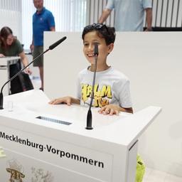 Ein Junge steht beim Tag der offenen Tür des Landtags im Plenarsaal am Rednerpult.