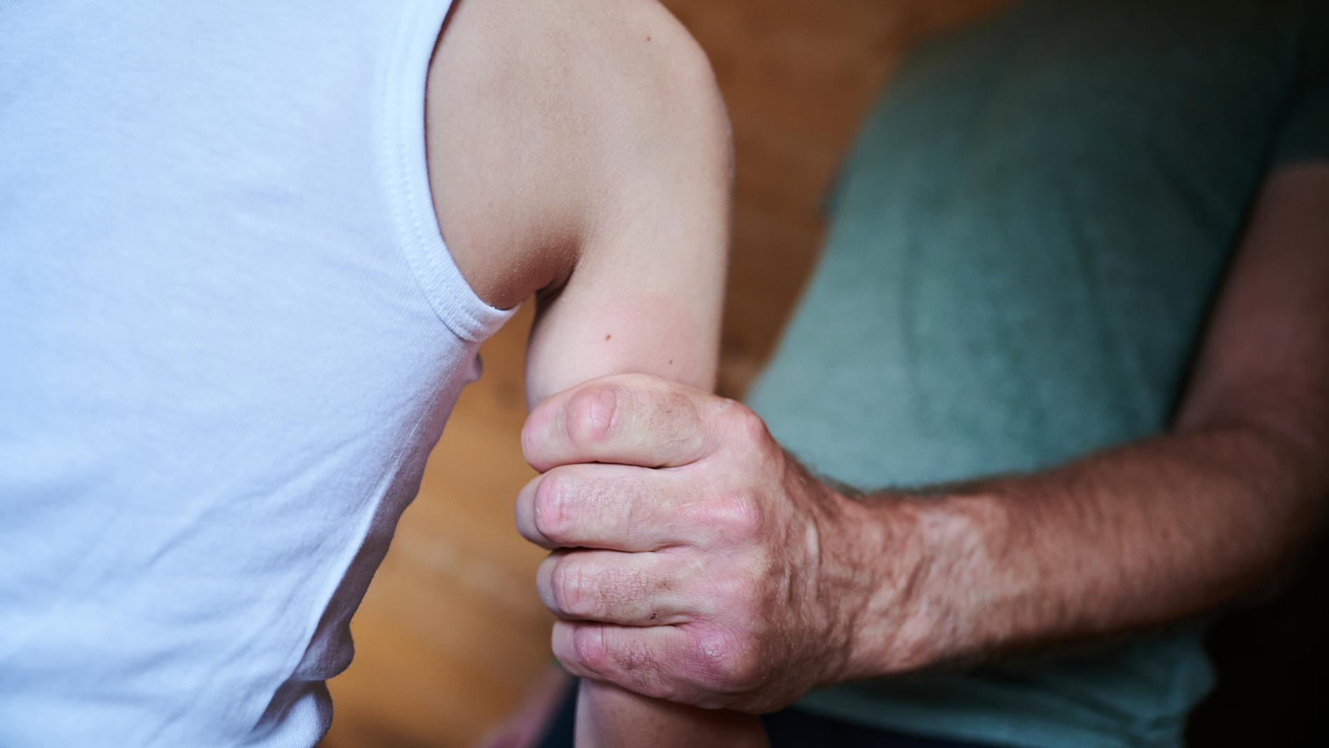 Ein Mann hält ein Kind fest am Arm (gestellte Szene). | Annette Riedl/dpa , Annette Riedl