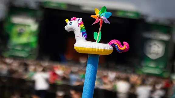 Scheeßel: Festivalbesucher strecken auf dem Gelände des Hurricane Festivals eine Schwimmhilfe mit einem aufgesteckten Badetier und Einhorn-Optik in die Höhe.