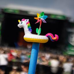 Scheeßel: Festivalbesucher strecken auf dem Gelände des Hurricane Festivals eine Schwimmhilfe mit einem aufgesteckten Badetier und Einhorn-Optik in die Höhe.