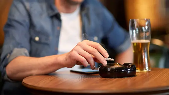 Wer wirklich von der Zigarette loskommen will, sollte alte Gewohnheiten ändern. | fotolia, Syda Productions Mann raucht bei einem Bier eine Zigarette.