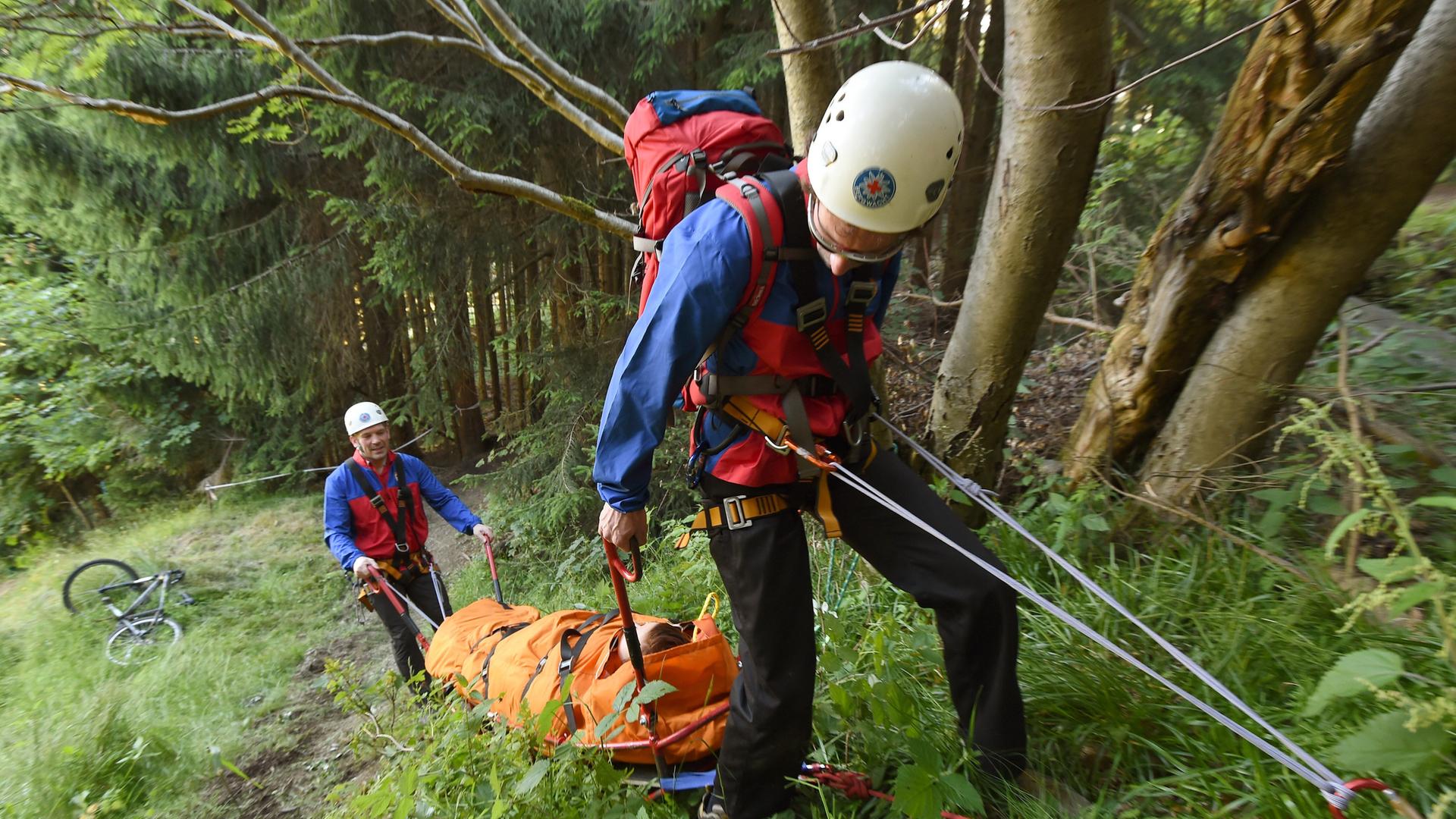 Zwei Einsatzkräfte der Bergwacht ziehen eine Person mit einer Faserseilwinde auf einer Gebirgstrage. | picture alliance / Swen Pförtner/dpa | Swen Pförtner