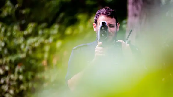 Ein polizist kontrolliert bei einer Verkehrskontrolle der Polizei mit einem Lasermessgerät die Geschwindigkeit des Autoverkehrs.