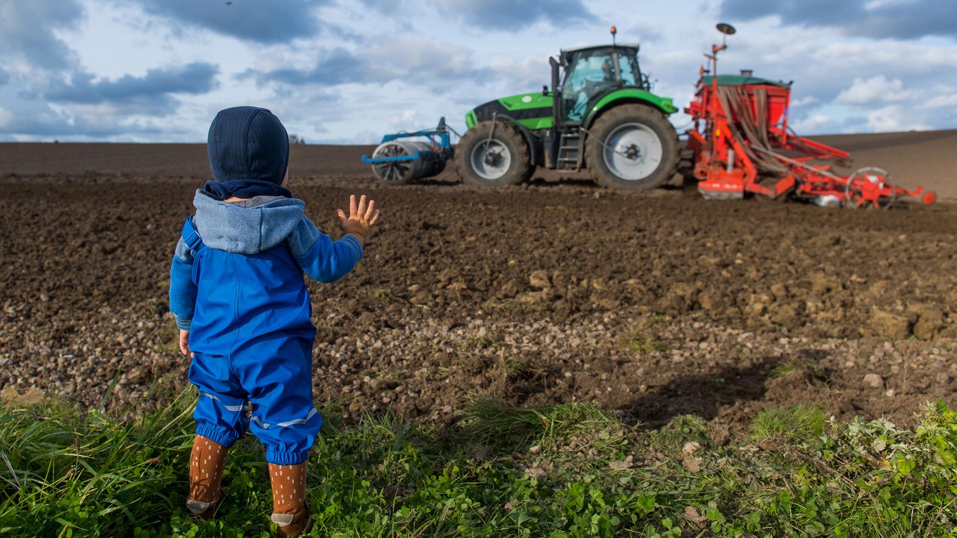 ein kind auf einem acker mit trecker im hintergrund | picture alliance,  dpa Themendienst, Benjamin Nolte