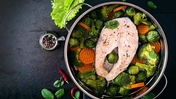 Lachssteak, Brokkoli, Möhrenstücke und Rosenkohl in einer Pfanne