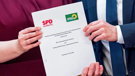Katharina Fegebank (Grüne) und Peter Tschentscher (SPD) halten den neuen rot-grünen Koalitionsvertrag in den Händen.