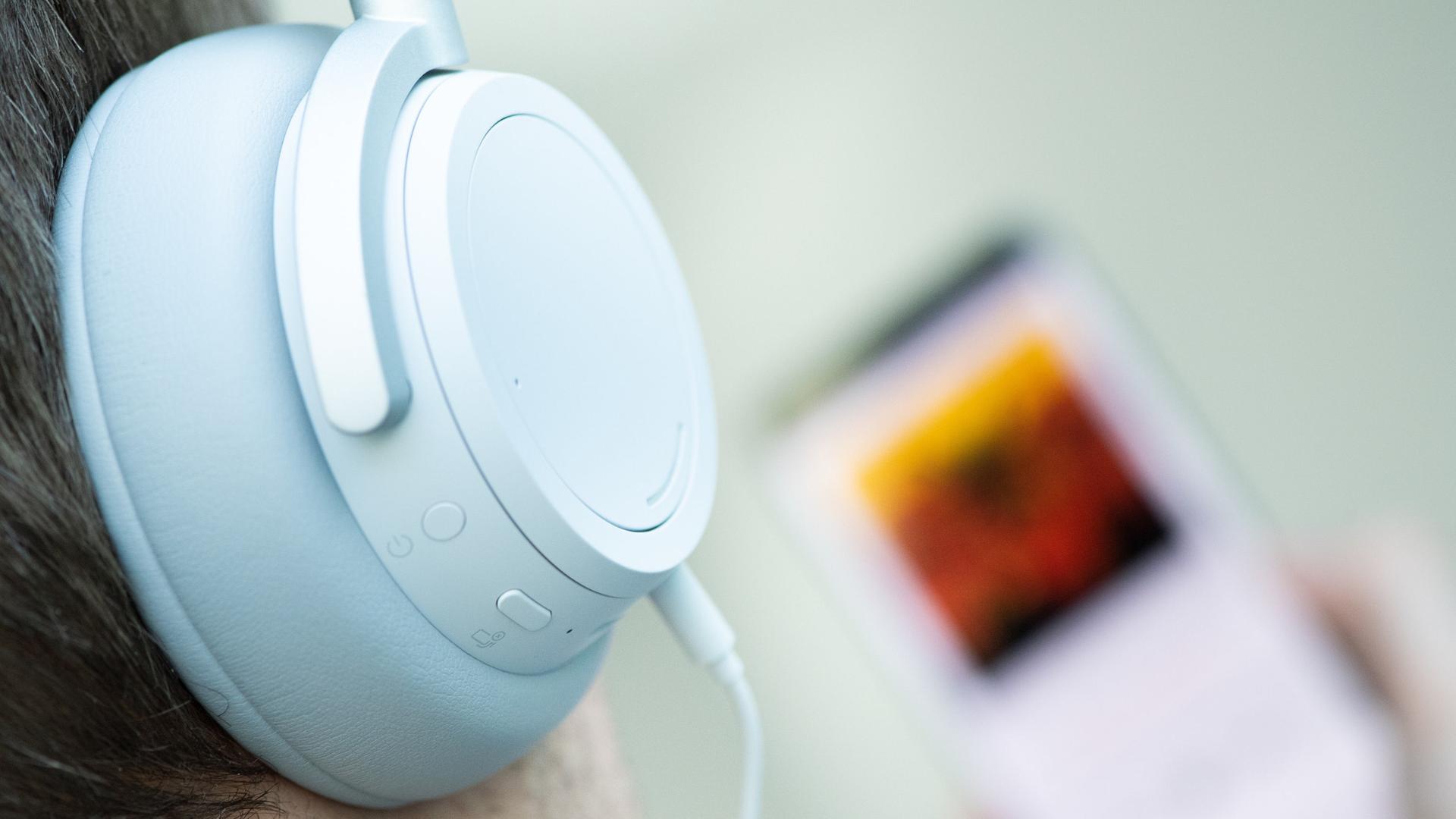 Ein junger Mann hört mit Kopfhörern einen Podcast von seinem Smartphone. | dpa, Franziska Gabbert