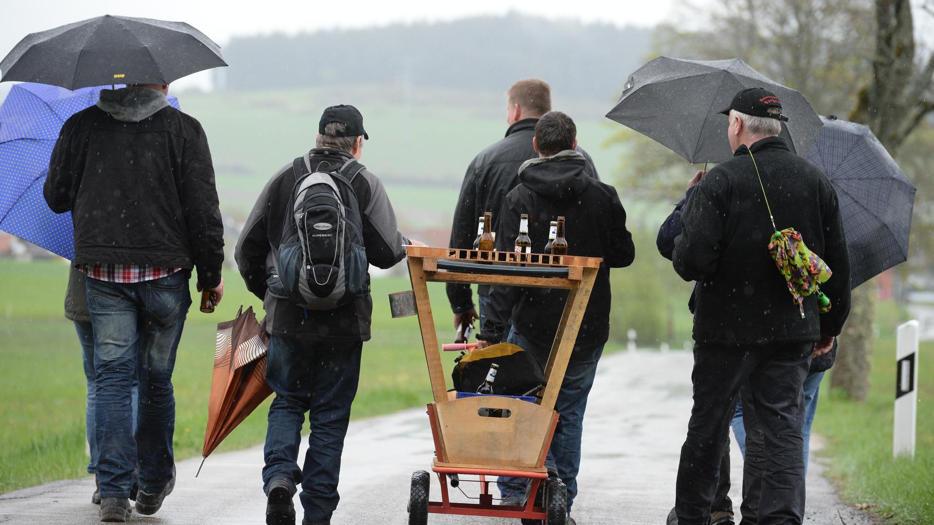 Bei regnerischem Wetter gehen Menschen mit Bollerwagen und Regenschirmen einen Straße entlang. | picture alliance / dpa | Patrick Seeger