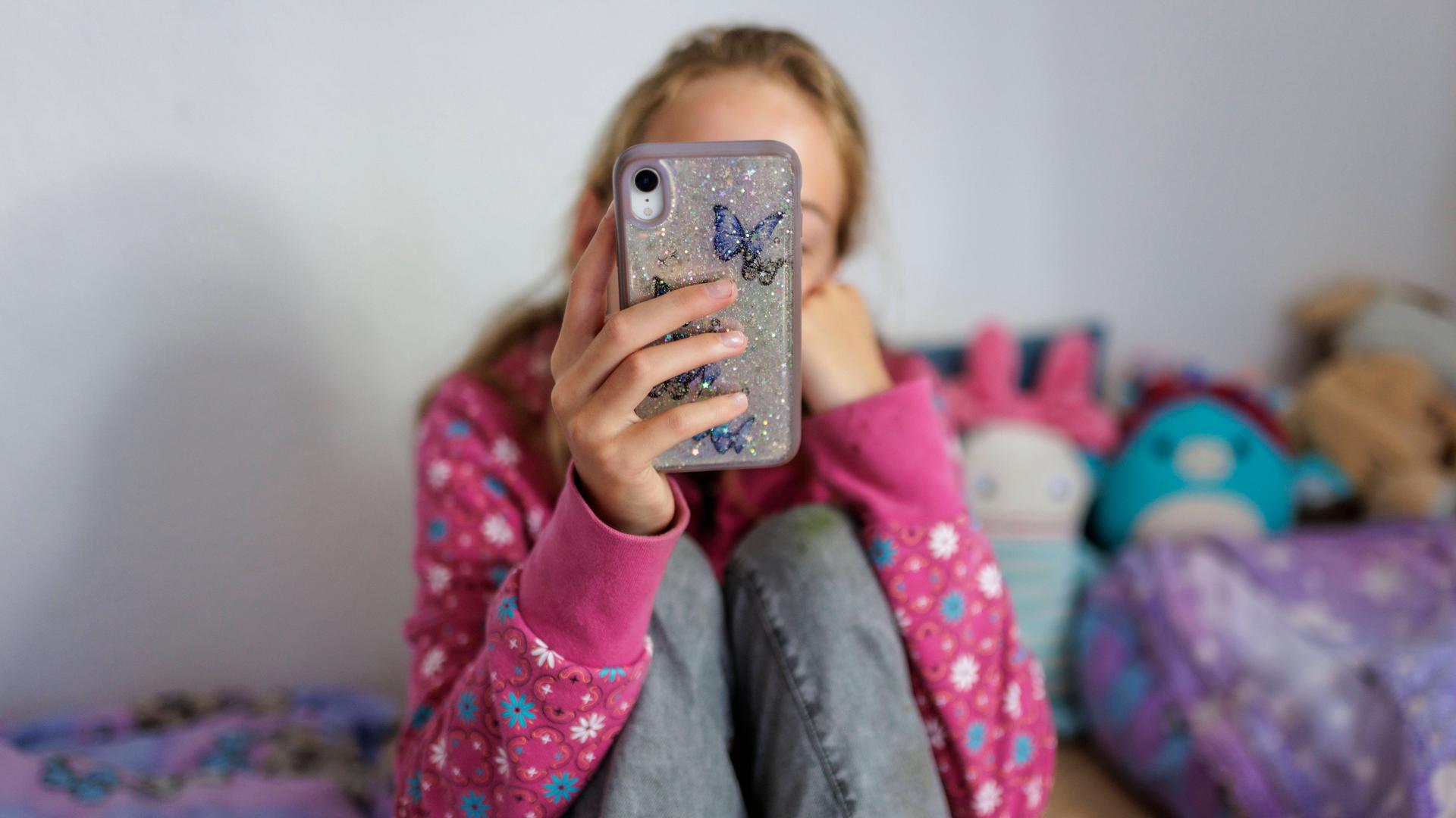 Symbolbild: Ein Mädchen mit einem Handy in der Hand | IMAGO / photothek