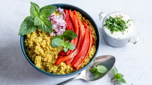 Eine Schale mit Couscous und Gemüse, dazu ein Glas mit Minzjoghurt.