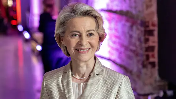 EU-Kommissionspräsidentin Ursula von der Leyen lächelt bei einer Veranstaltung in die Kamera.