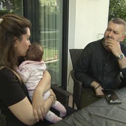 Eine Frau mit Baby und ein Mann, der besorgt schaut, sitzen zusammen am Tisch.