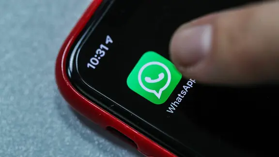 Ein Finger tippt auf einem Smartphone auf die App WhatsApp.