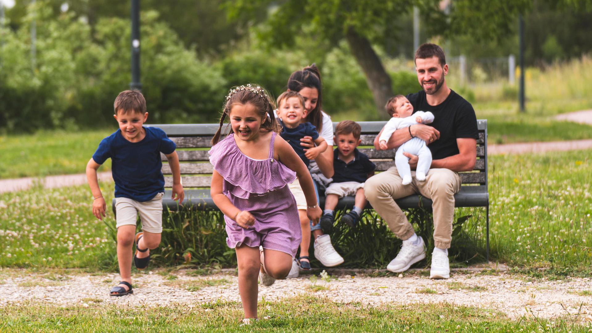 Eine Familie sitzt auf einer Parkbank im Grünen. | picture alliance, Josu Acosta
