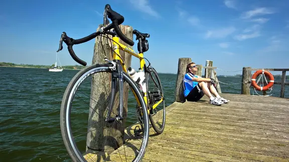 Ein Fahrrad und ein Radler auf einem Holzsteg an der Schlei.