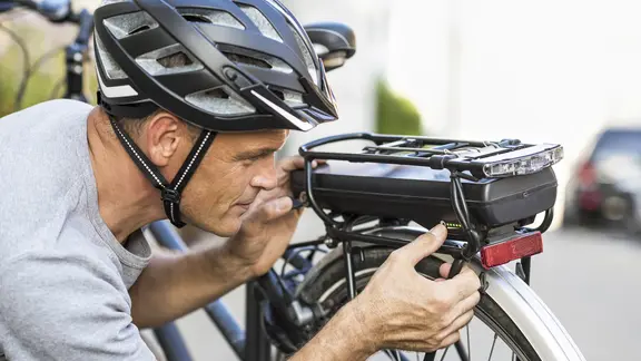 Ein Mann blickt auf den Akku seines E-Bikes. | Imago Images / allOver-MEV Ein Mann blickt auf den Akku seines E-Bikes.