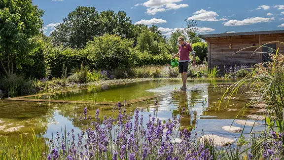 Peter Rasch geht in einem Schwimmteich über eine Begrenzung.