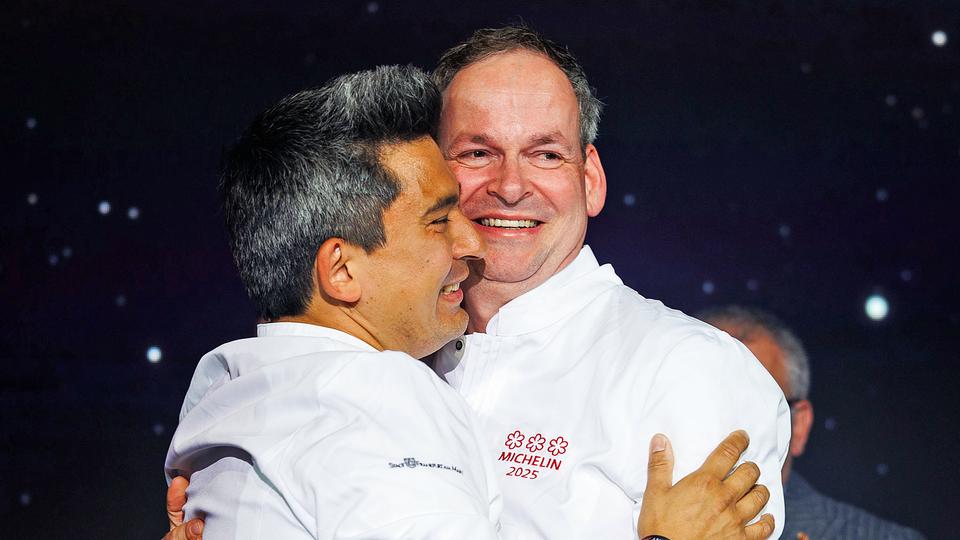 Christoph Rüffer (r.) ist Küchenchef im mit drei Sternen ausgezeichneten "Restaurant Haerlin" in Hamburg. | dpa Bildfunk, Lando Hass Preisträger Christoph Rüffer aus Hamburg (r.) steht bei der Verleihung der Guide-Michelin-Sterne 2025 neben seinem Kollegen Tohru Nakamura aus München.
