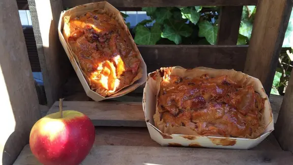 Zwei frisch gebackene Apfelbrote, daneben ein Apfel.